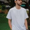 man in white crew neck t-shirt standing on green grass field during daytime